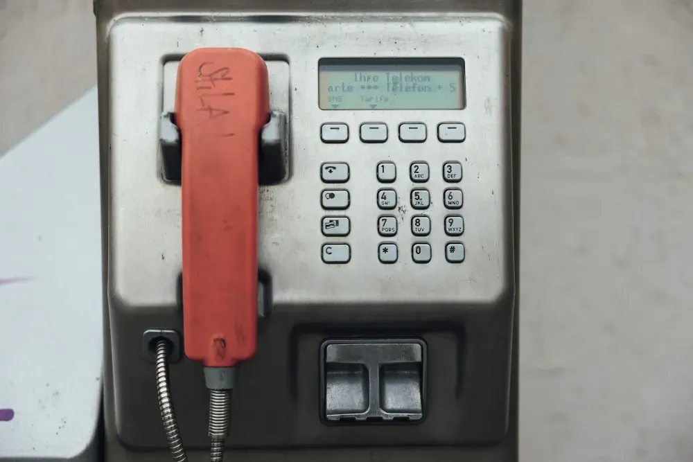 an old style pay phone with a red dial